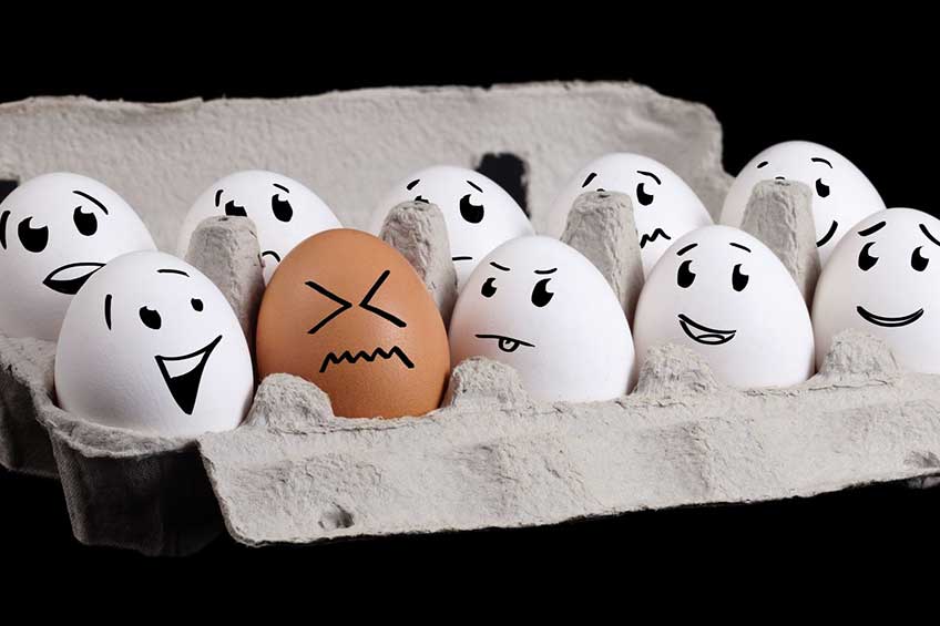White eggs with faces laughing at brown egg